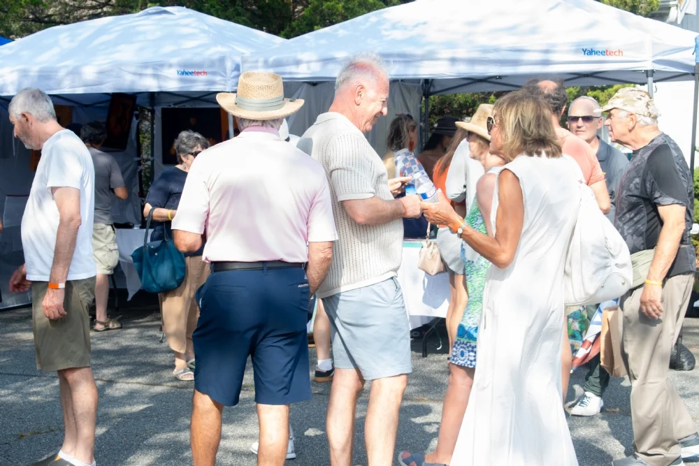 Guests smiling and chatting among the art vendor tents