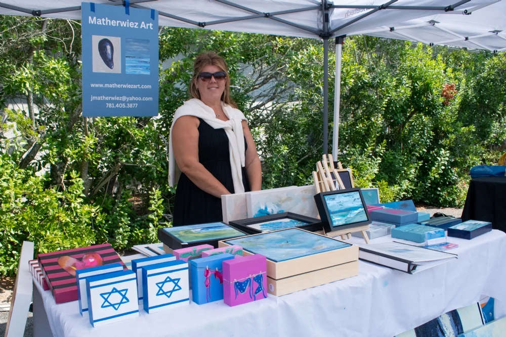 A smiling local artist at her art vendor booth